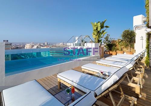 Small glass-walled pool surrounded by loungers with views of the city